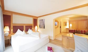 A modern hotel room with a large bed and cozy furnishings. There is a desk and pleasant lighting.
