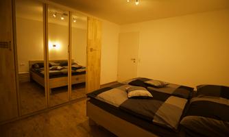 A modern bedroom with a large bed and mirrors. The walls are bright and the room feels inviting.