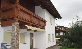 A beautiful house with a large balcony in alpine style. The garden is green and inviting, ideal for relaxed hours outdoors.