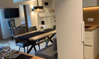 A modern apartment with an open living area and a kitchen. The dining area is equipped with a table and chairs.