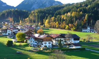 A picturesque village surrounded by mountains and colorful forests. The houses are located in a green landscape that radiates tranquility and idyll.
