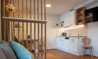 A modern living environment with a well equipped kitchen and a dining area. The decor is bright and inviting, with wooden details and a cozy atmosphere.