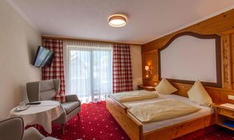A cozy hotel room with two beds and a balcony. The decor is modern and inviting, with a television and a small table.