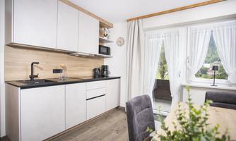 A modern kitchen with bright cabinets and an elegant countertop. Through the window, there is a beautiful view of nature.