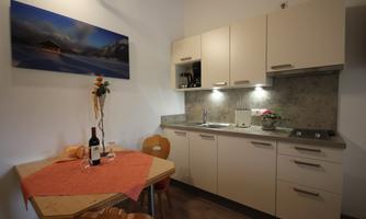 A modern kitchen with light cabinets and a cozy dining area. Wine and glasses are on the table, while a decorative plant beautifies the space.