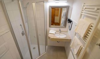 A modern bathroom with a shower and a sink. Towels are neatly placed on a towel rack.