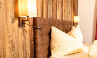 A cozy bedroom with an upholstered headboard and wood paneling. Soft lighting creates a relaxed atmosphere.