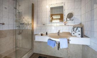 A modern bathroom with a glass shower and a large mirror. Towels and toiletries are on the sink.
