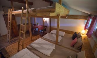 A cozy room with a bunk bed and wooden furniture. There is a staircase, a table, and soft lighting.