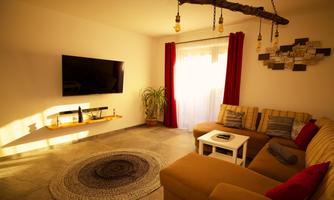 A modern living room with a television, a comfortable couch, and a coffee table. Large windows let in plenty of daylight and create an inviting atmosphere.
