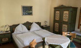 A cozy bedroom with a double bed and typical rustic wooden furniture. A picture hangs on the wall, and a small table with chairs is in the room.