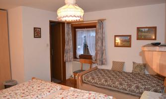 A cozy room with two beds and warm lighting. Decorative pictures hang on the walls, and curtains let light through.