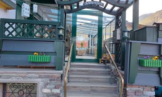 An inviting entrance area with a green door and wooden steps. Flower boxes and a canopy create a cozy atmosphere.