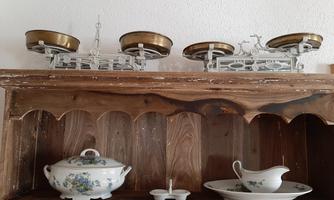 A wooden shelf with various pieces of dishware, including a soup bowl and a sauce dish. At the top, two elegant scales are visible.