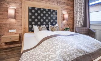 A cozy bedroom with wooden walls and a large bed. The room is stylishly decorated and has soft lighting.