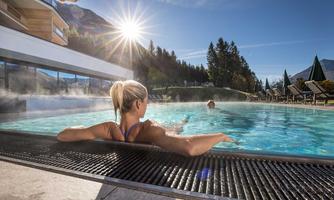 A relaxing swimming pool in the mountains on a sunny day. In the water, two people are enjoying the calm atmosphere.