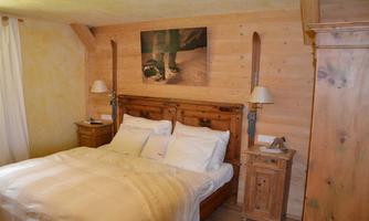 A cozy bedroom with a wooden bed frame and two nightstands. The walls are made of wood, and a piece of art hangs above the bed.