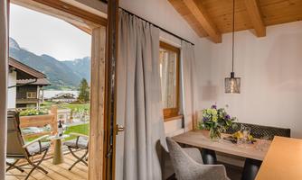 A cozy corner with a dining area and a small table. Through the open window, you can see the mountains and the garden outside.