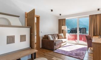 A modern room with a cozy sofa and a desk. Large windows offer a view of the mountains and plenty of daylight.