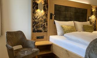 A modern bedroom with a cozy bed and elegant wooden furniture. The room is designed with warm light and stylish decorations.