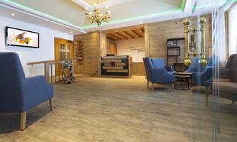 A modern reception area with wooden decor and elegant lighting. Cozy blue armchairs create an inviting atmosphere.