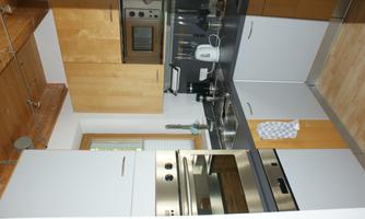 A modern kitchen with wood and gray cabinets. It is well equipped with a stove, a microwave, and a sink.
