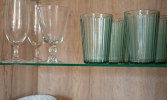 A shelf with various dishware, including bowls, mugs, and glasses. The materials are designed in different colors and patterns.