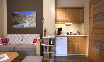A cozy holiday apartment with a bright living room and a small kitchen. A picture of a picturesque landscape hangs on the wall.
