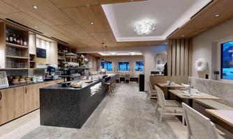 A modern café with wooden shelves and a cozy atmosphere. There is a bar and tables for lingering.