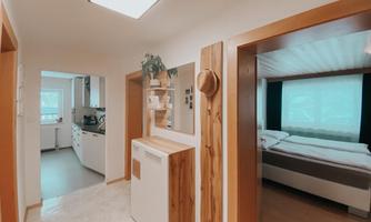A bright hallway with modern design. On the left side is the kitchen and on the right side a cozy bedroom.