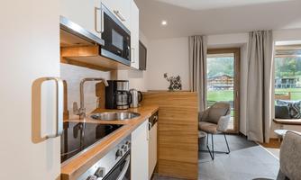 A modern kitchenette with modern appliances and a cozy dining area. Large windows offer a view of the landscape.