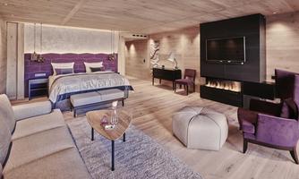 A modern and elegant hotel room with a large bed and stylish furniture. The warm wood appearance creates an inviting atmosphere.