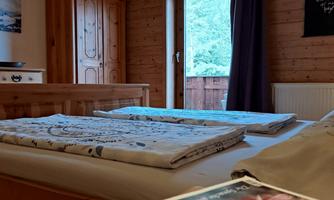 A cozy bedroom with wood paneling and two beds. The room has access to the balcony and views of the outdoors and modern decorative elements.
