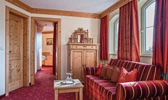 A cozy living space with a red sofa and wooden ceilings. The room has large windows and warm colors.