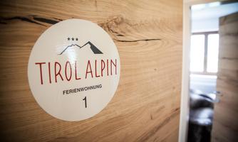 A sign with the inscription "Tirol Alpin" and room number 1. The background is made of light wood, creating a cozy atmosphere.