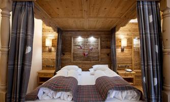 A cozy bedroom with a wooden frame bed and soft lighting. The walls are made of wood, creating a warm atmosphere.