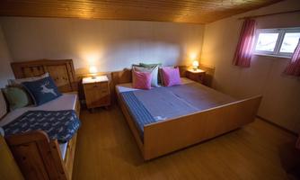A cozy bedroom with two beds and wood paneling. Soft lighting and colorful cushions create an inviting atmosphere.
