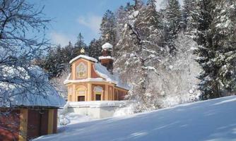 A picturesque church in the snowy forest. The ground is covered with fresh snow, and the surroundings radiate winter tranquility.