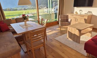 A bright and inviting living room with wooden furniture. Large windows provide a beautiful view of the landscape.