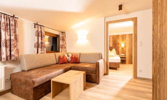 A cozy living room with a couch and a wooden table. The room has warm colors and creates an inviting atmosphere.