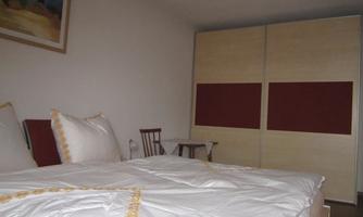 A cozy bedroom with a large bed and comfortable pillows. In the background, there is a spacious wardrobe.