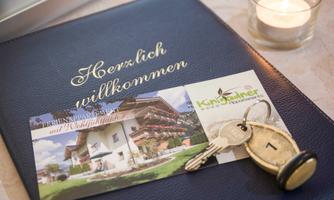A welcome letter on a blue folder with a key and a card. The card shows an accommodation and invites you to stay.