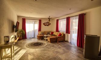 A cozy living room with a comfortable sofa and large windows. Red curtains give the room an inviting atmosphere.