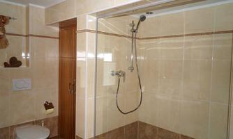 A modern bathroom with a shower and a toilet. The walls are designed with light tiles.