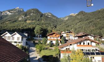 A picturesque mountain landscape with traditional houses and green trees. The surroundings are calm and inviting, perfect for a relaxing stay in nature.