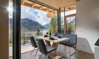 A modern dining room with a table, chairs, and a view of the mountains. Large windows let in plenty of light and offer a nice view outside.