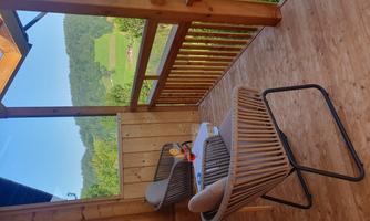 A cozy terrace with two chairs and a small table. In the background, a green landscape with hills stretches out.