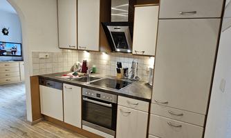 A modern kitchen with bright cabinets and a stone countertop. There are cooking appliances and kitchen utensils arranged on the table.