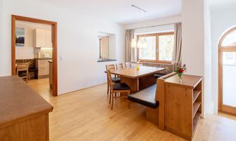 A bright dining room with a large table and chairs. There are large windows that let in plenty of light.