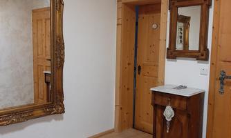 An inviting hallway with a large mirror and a wooden dresser. The walls are in soft colors, and there is a welcome mat on the floor.